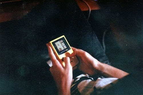 Hands holding a yellow Game Boy playing Tetris